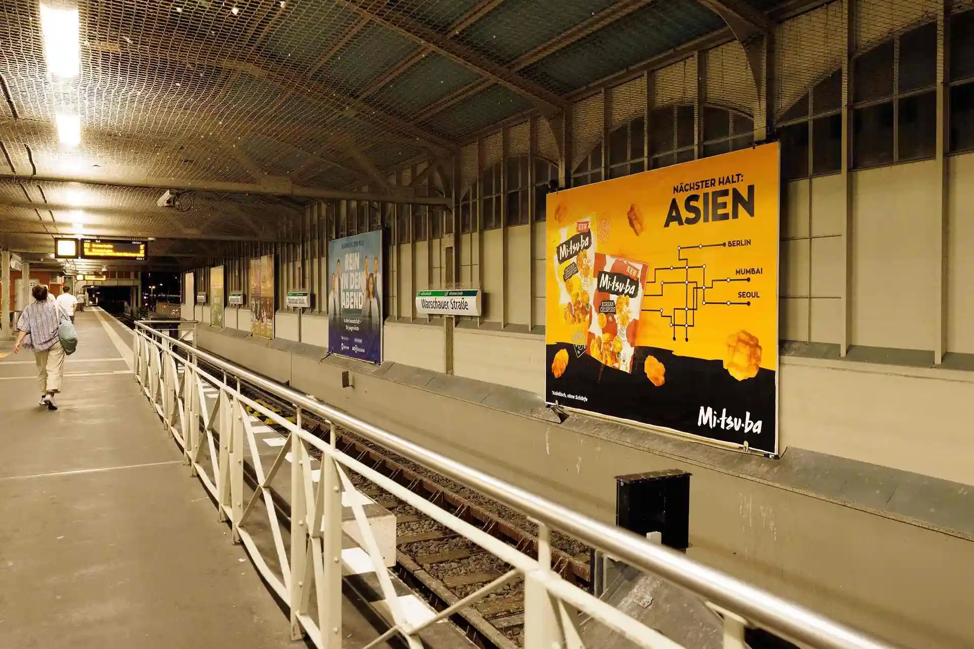 Mitsuba-Plakat an einem Metroboard in einer Berliner U-Bahnstation.
